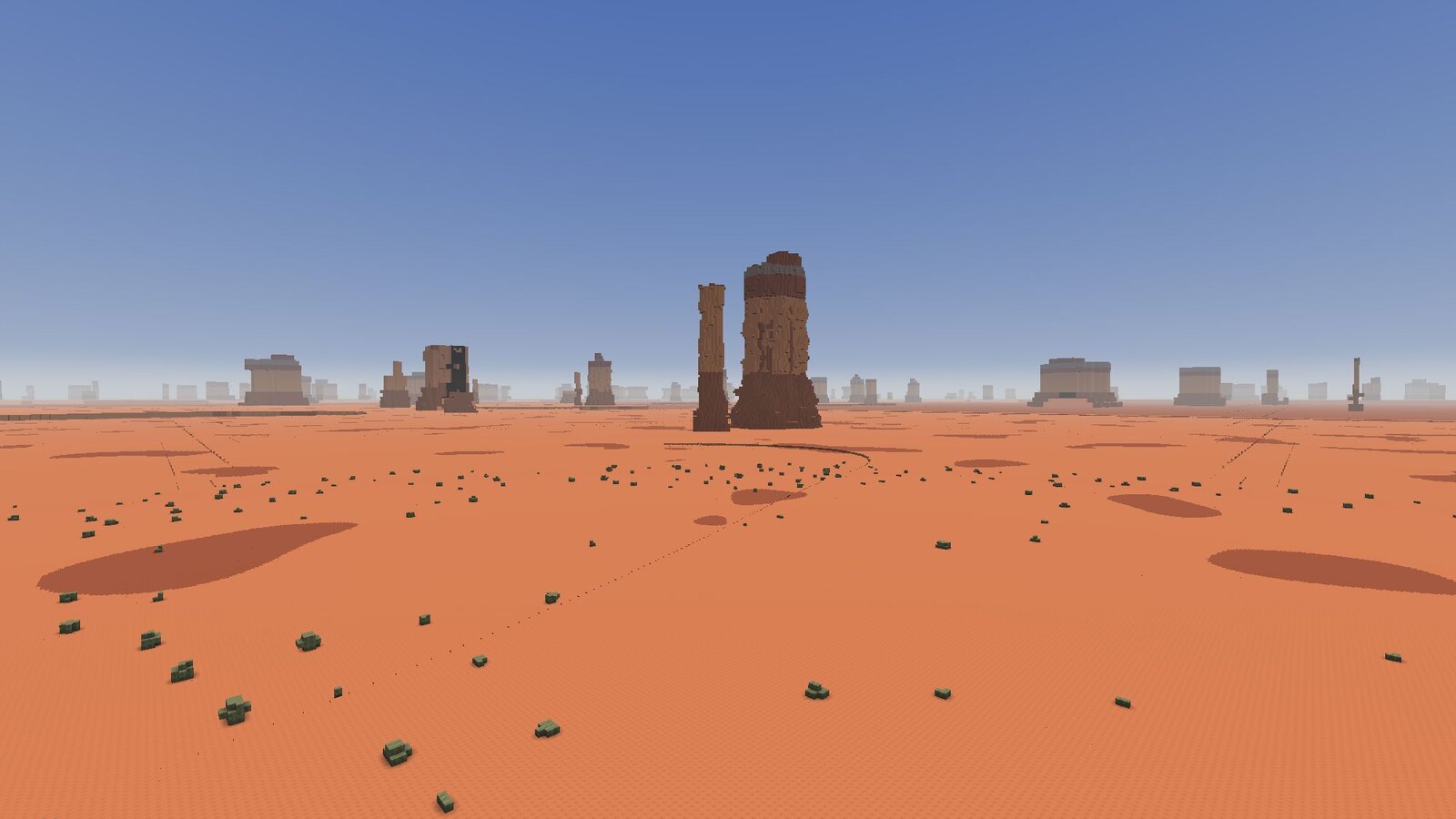Red desert with a sandstone butte and a spire, and a line of more of them fading into haze along the horizon.